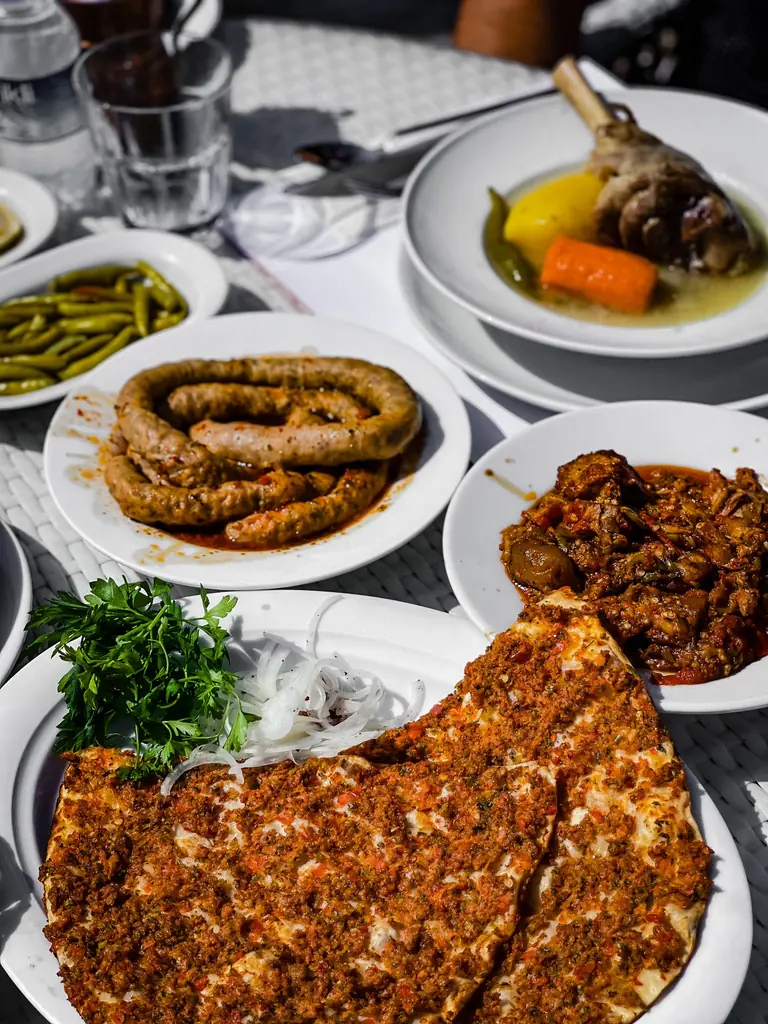 Masada lahmacun, ızgara sucuk, kelle paça ve közlenmiş biber tabakları
