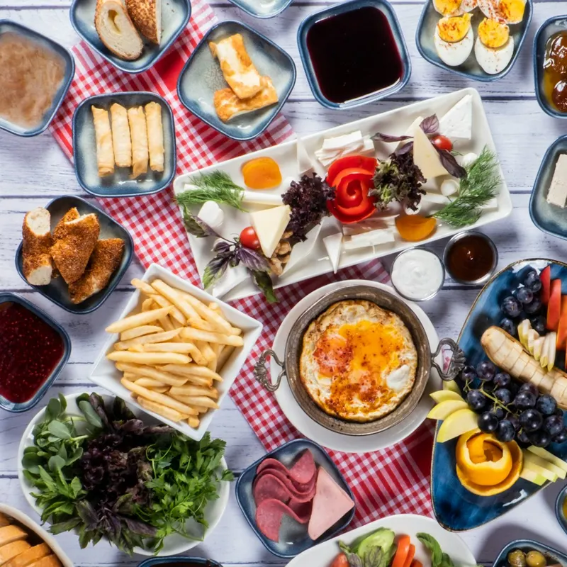 Üstten çekilmiş serpme kahvaltı sofrası: peynir tabağı, sigara böreği, zeytin, reçel ve yumurta